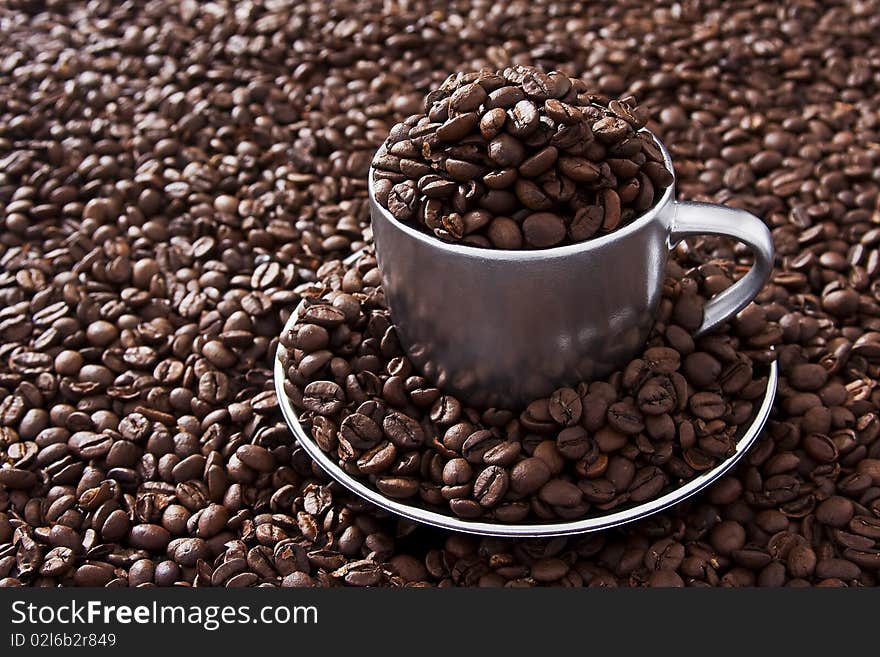 Coffee beans on the table and into a cup. photo studio and captured in RAW file post-processing software professional. Coffee beans on the table and into a cup. photo studio and captured in RAW file post-processing software professional.