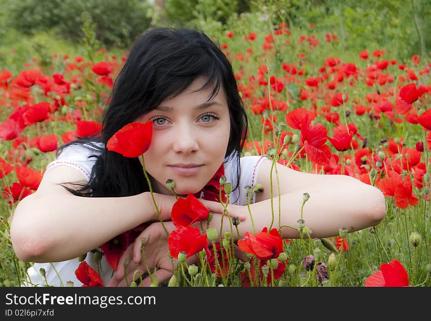 Beautiful Brunette Girl in a Red Poppies field