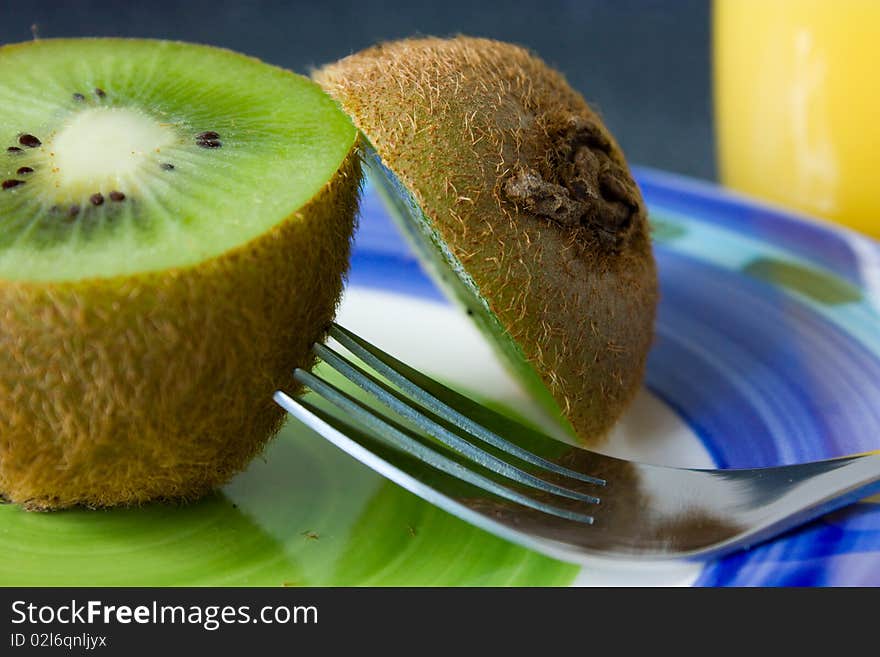 Kiwi, fork and orange juice on a plate