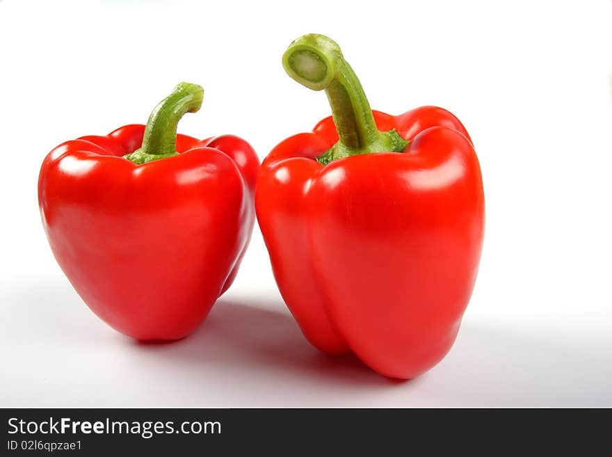 Two red pepers with green stacks on white background. Two red pepers with green stacks on white background