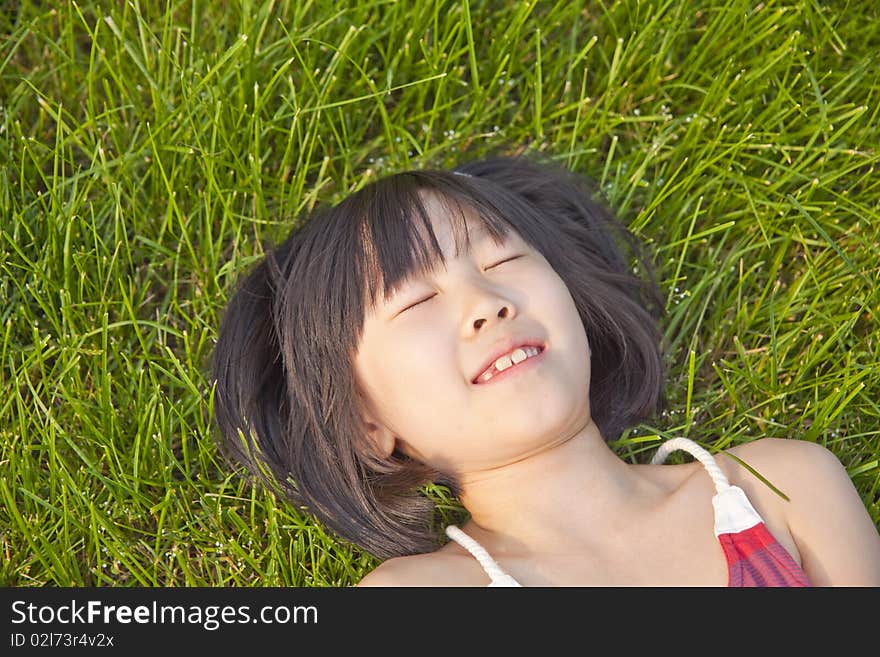 The asian girl is lying on green grass in summer. The asian girl is lying on green grass in summer