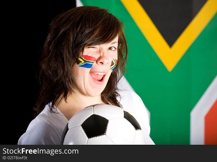 Happy young soccer supporter, flags on her cheeks, holds football ball, south africa flag as background. Happy young soccer supporter, flags on her cheeks, holds football ball, south africa flag as background