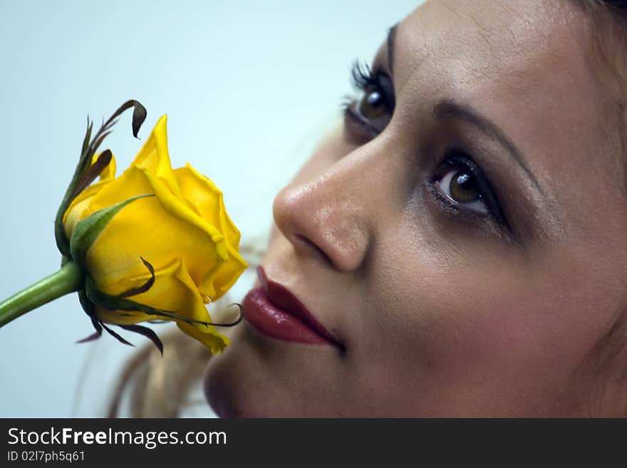 Portrait of the beautiful young woman holding single yellow rose flower.