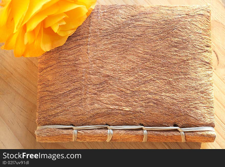 Single yellow rose on a book with a textured handmade cover