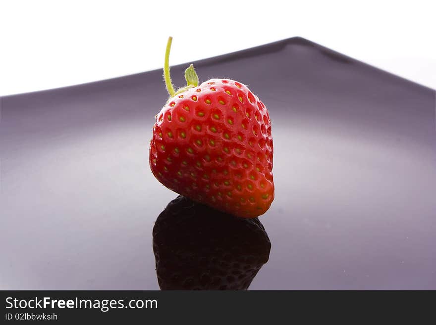 Red strawberry on black plate isolated on white