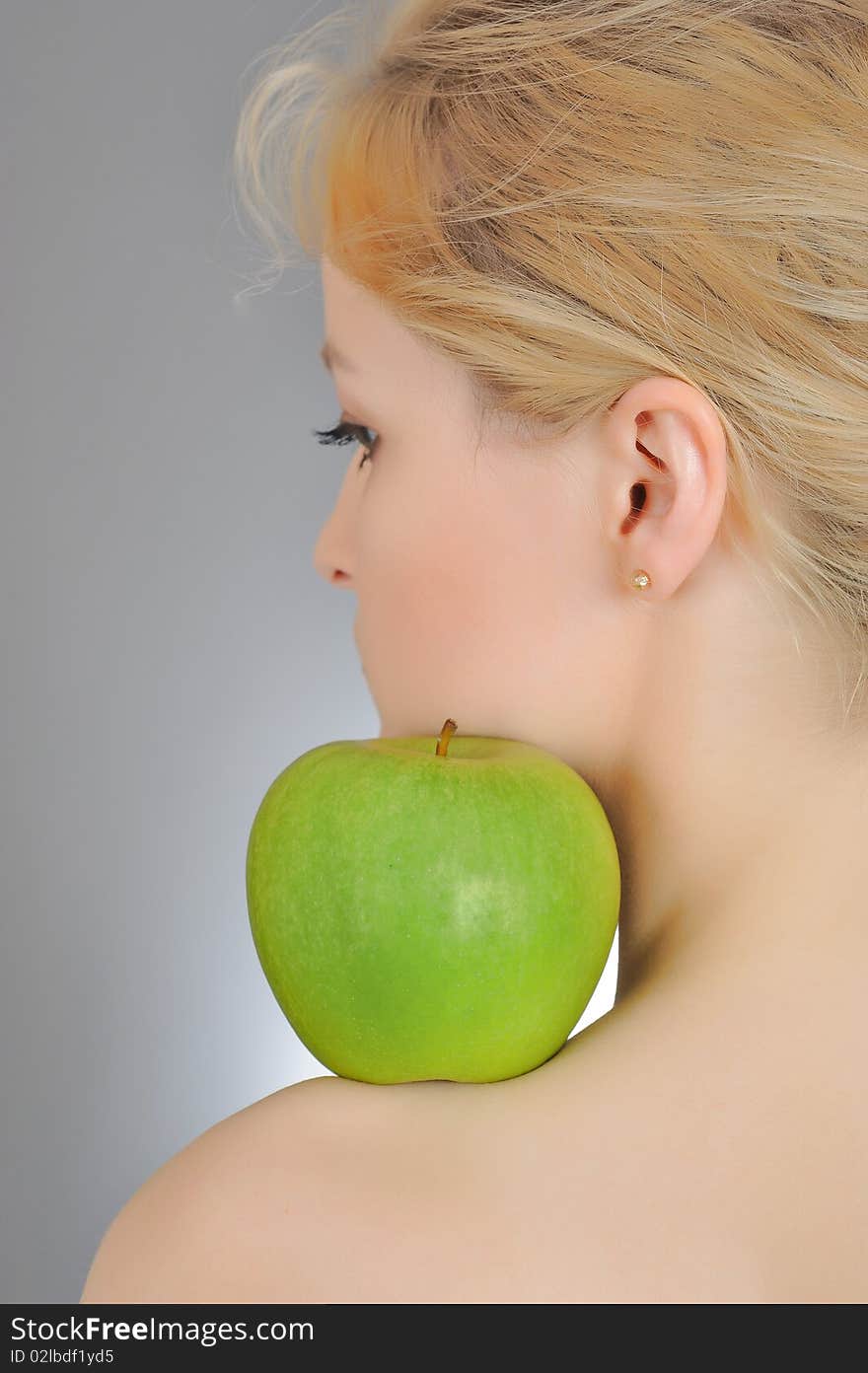 Young woman holding green apple on  her shoulder