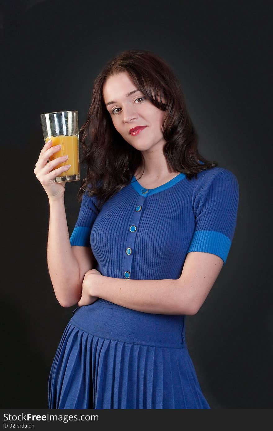 Beauty woman in blue dress with yellow orange juice on black background