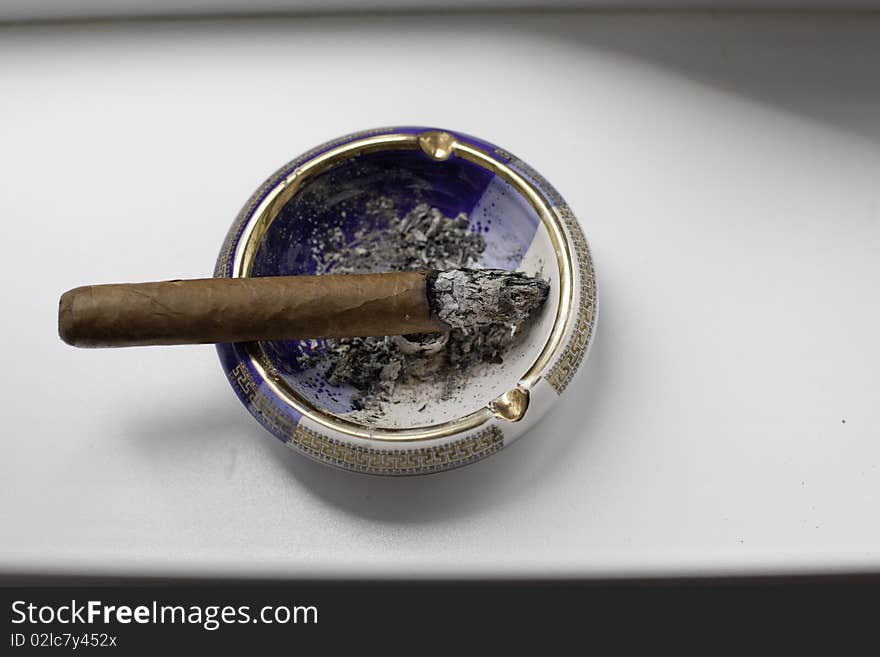 Cuban cigar on an elegant ashtray over a white background. Cuban cigar on an elegant ashtray over a white background