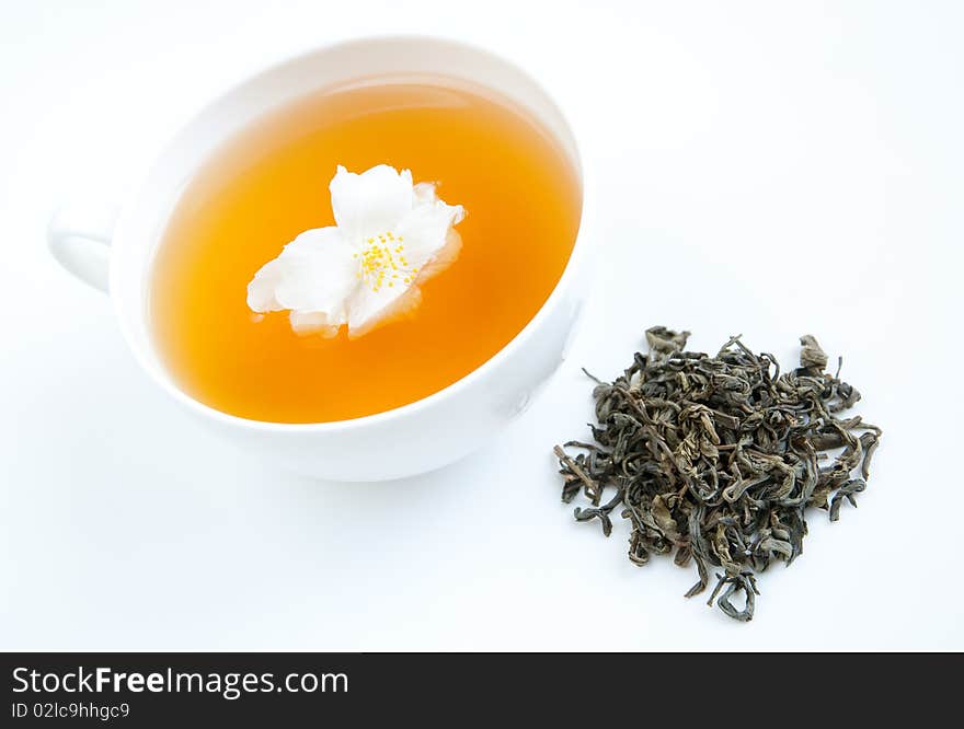 A cup of tea on a tray with dried tea leaves and jasmine flower, isolated on white