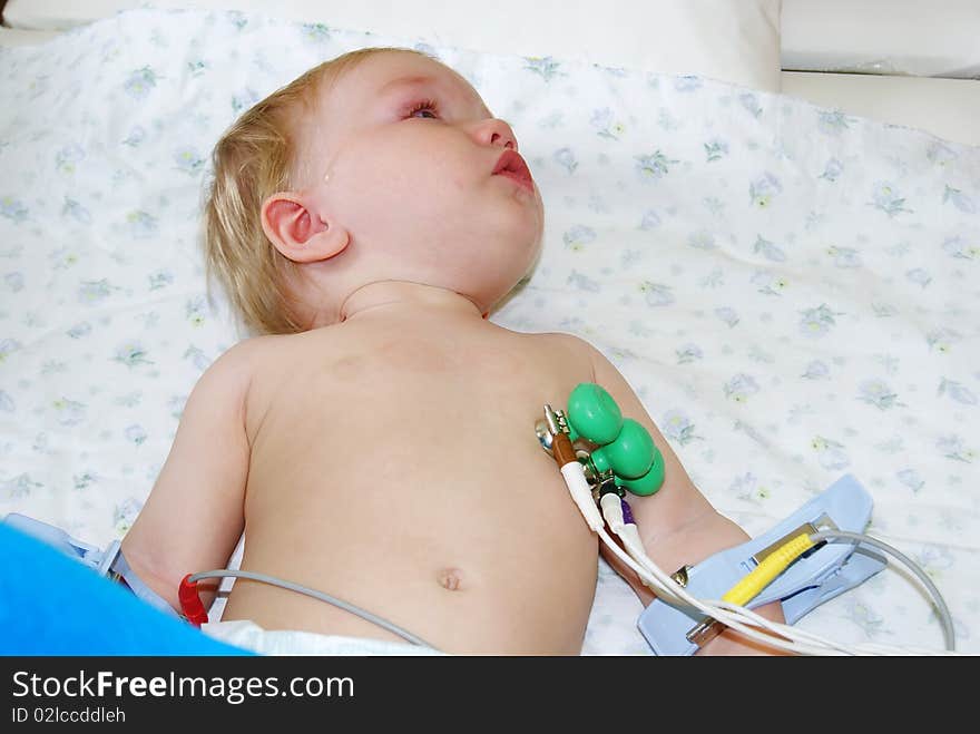 The little boy with tear-stained eyes lays on a couch in hospital and to it do the heart cardiogramme. The little boy with tear-stained eyes lays on a couch in hospital and to it do the heart cardiogramme