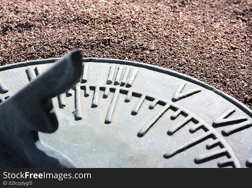 Ancient sundial lies on a dark ground.