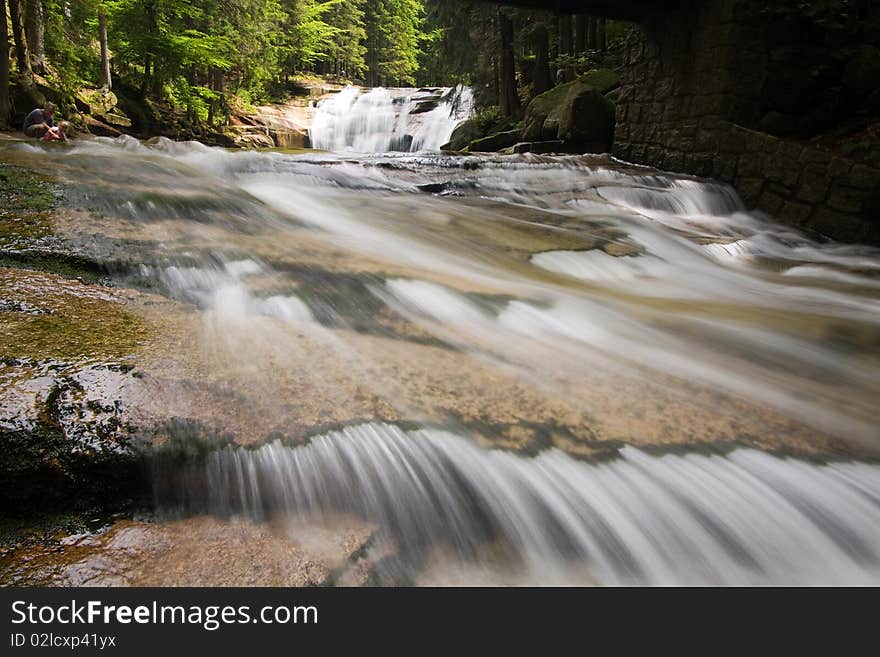 Stream below waterfall, stones and wood