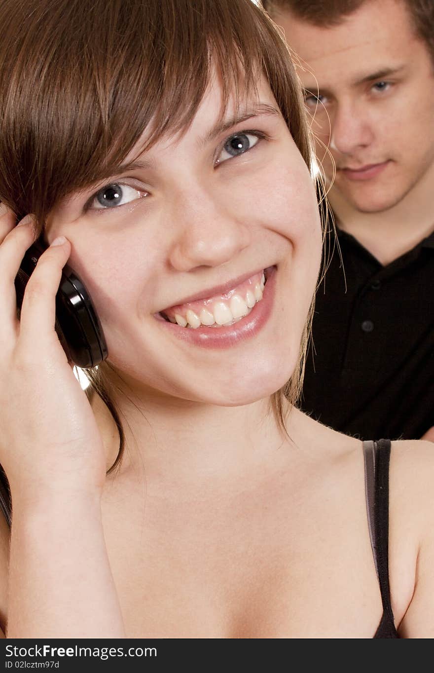 Young woman is phoning and her boyfriend is suspicious. Young woman is phoning and her boyfriend is suspicious