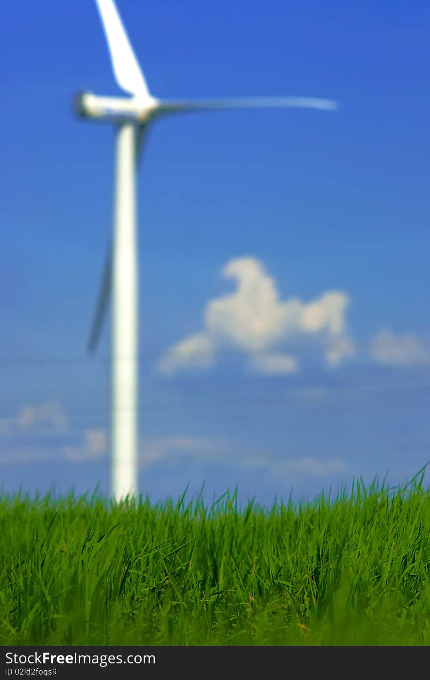 Ecological concept of grass closeup with blurry wind power in background. Ecological concept of grass closeup with blurry wind power in background.