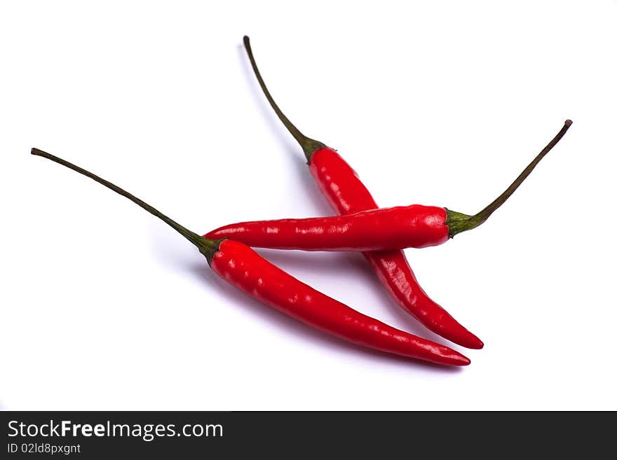 Three red chillies on a white background