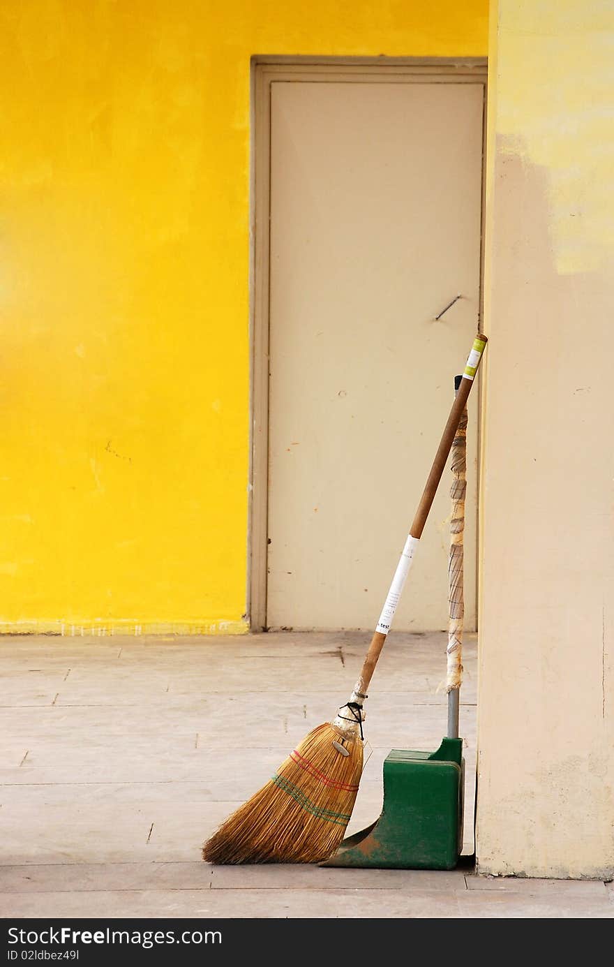 Broom and dustpan on a yellow wall