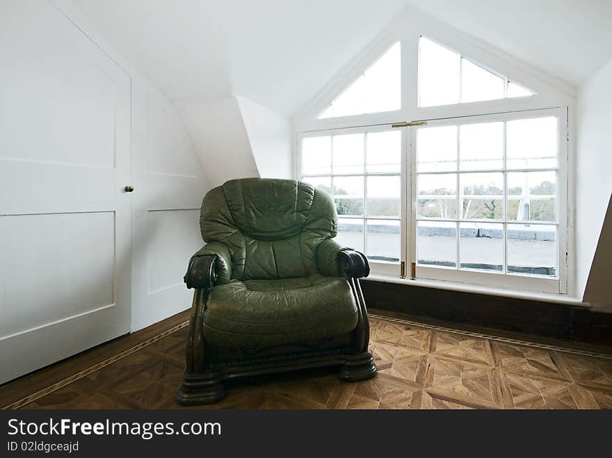 Detail shot of a living room with a bay window and green vintage leather armchair. Detail shot of a living room with a bay window and green vintage leather armchair