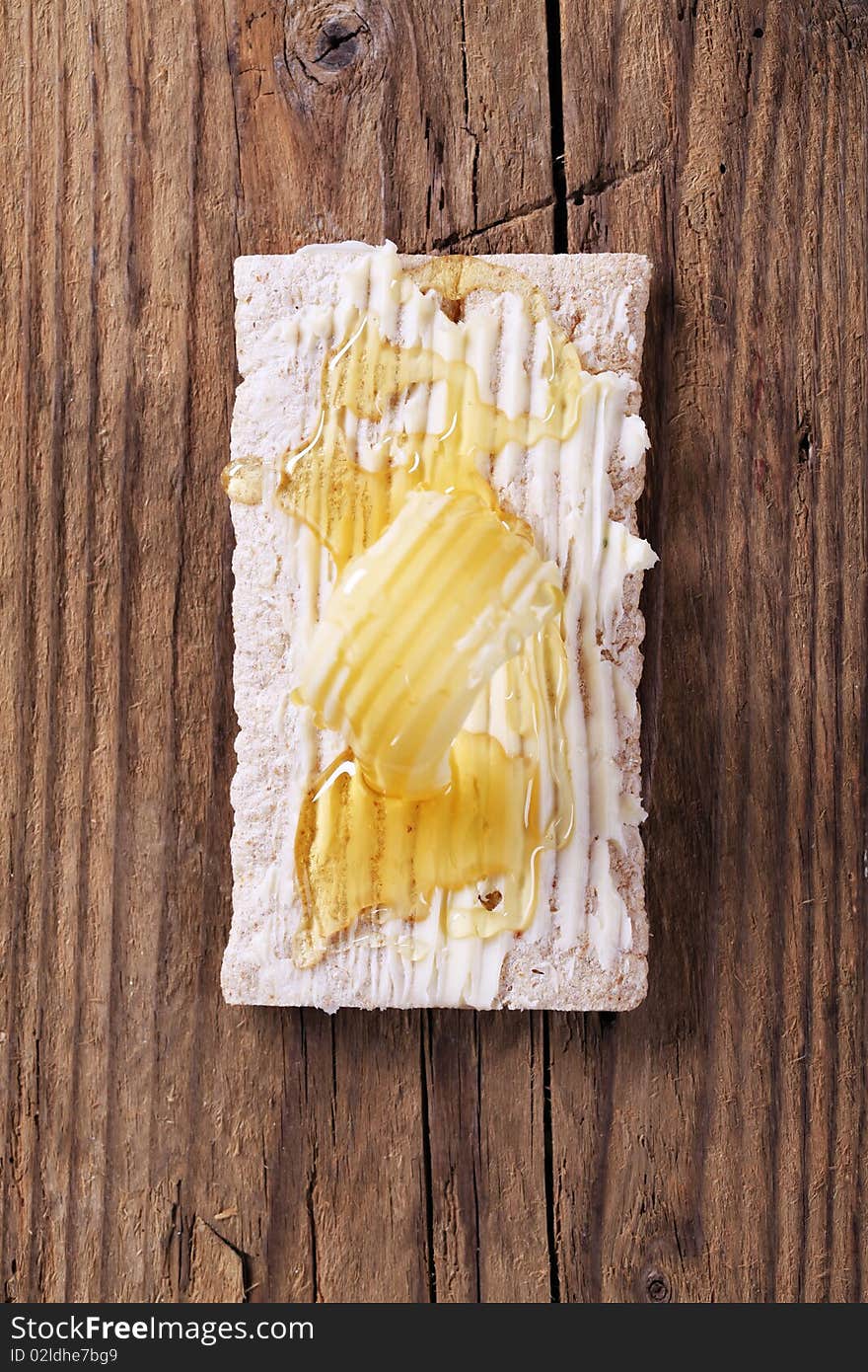 Slice of crispbread, butter and honey - overhead. Slice of crispbread, butter and honey - overhead