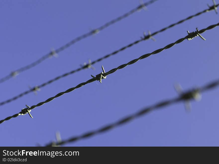 Barbwire (barbed wire) in front of the bright blue sky.