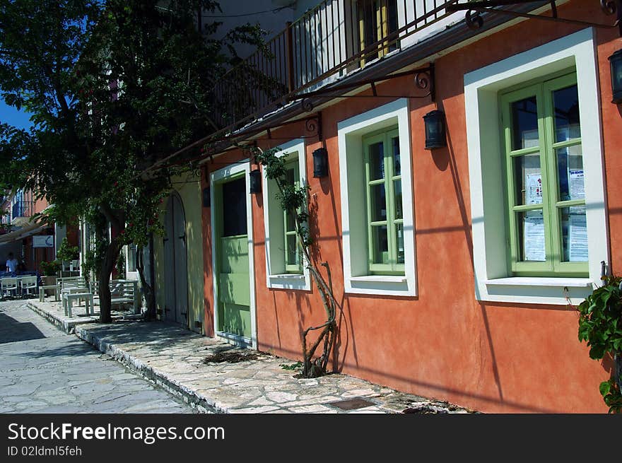 Orange vivid facade with green windows and white frames, mediterranean style. Orange vivid facade with green windows and white frames, mediterranean style.