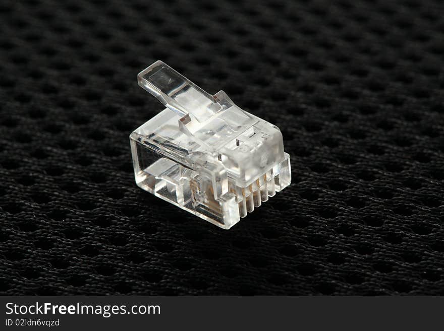 Connector for telephone cable on a black background. Connector for telephone cable on a black background