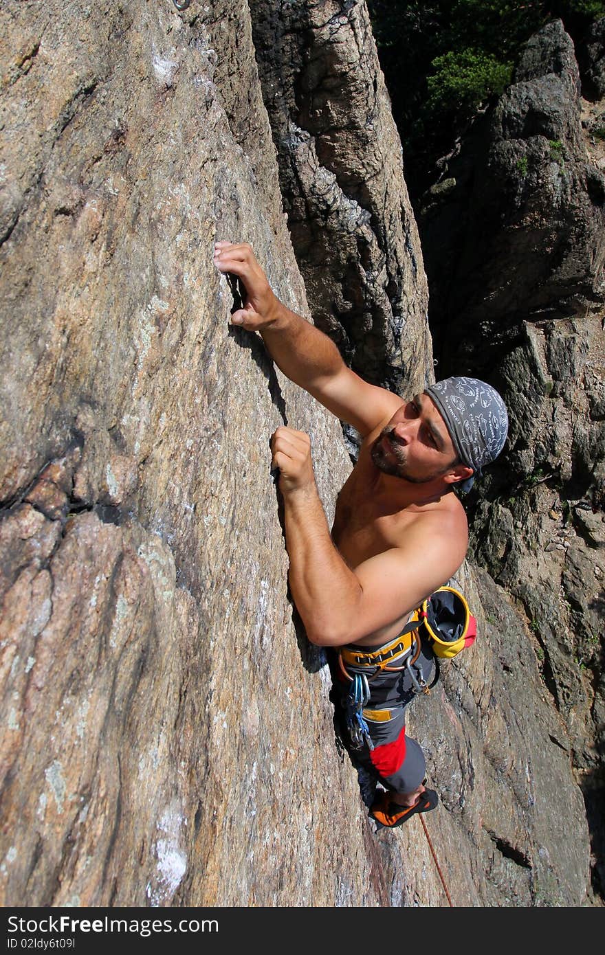 Male rock-climber  on a granite wall. Male rock-climber  on a granite wall