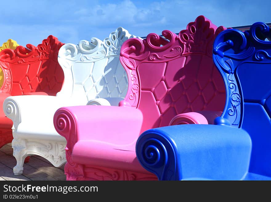 Multi-colored armchairs stand outdoor against the background the blue sky. Multi-colored armchairs stand outdoor against the background the blue sky