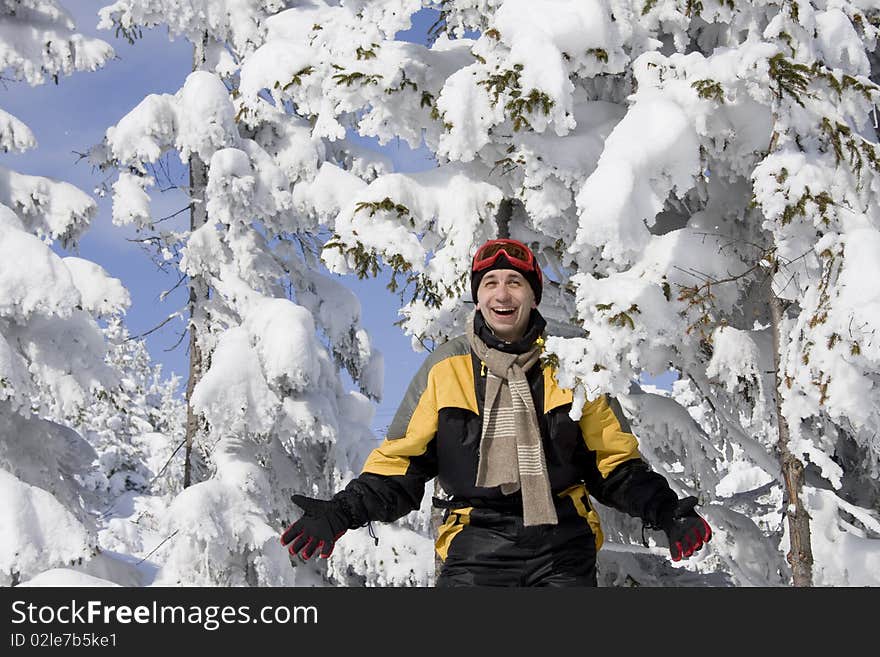 Young man a skier widely smiles on a background snow-bound fir-trees. Young man a skier widely smiles on a background snow-bound fir-trees