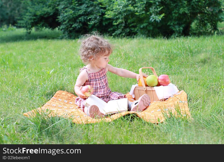 Small lovely girls with fruits and book in the park. Small lovely girls with fruits and book in the park