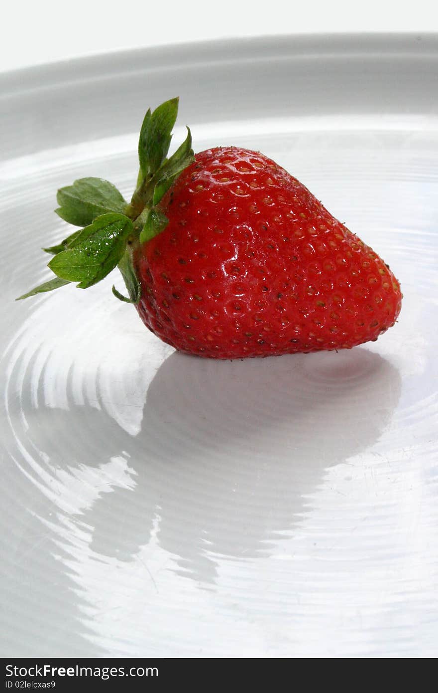 An isolated red strawberry on white dish