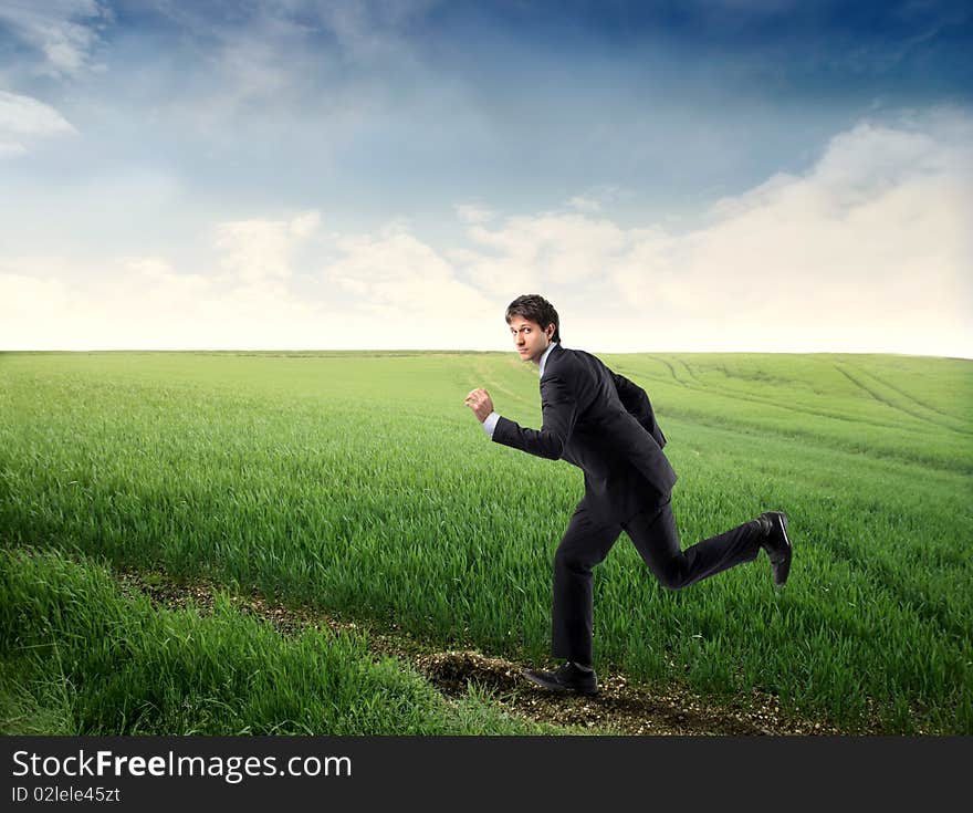 Young businessman running on a green meadow. Young businessman running on a green meadow