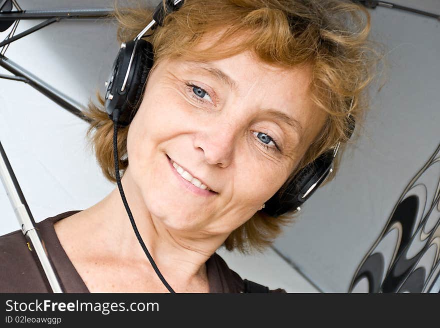 Portrait of middle-aged woman under an umbrella in your headphones