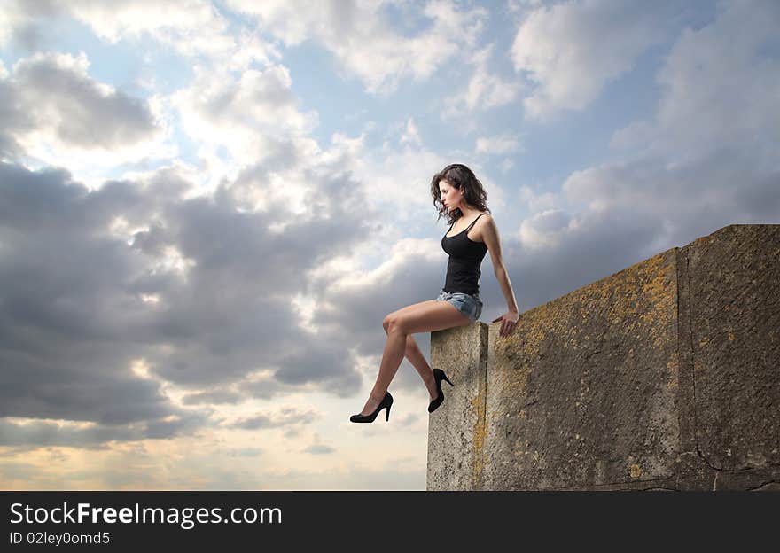 Beautiful woman sitting on a rock. Beautiful woman sitting on a rock