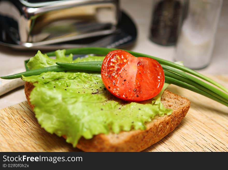 Sandwich with salad leaves, an onions and a tomato