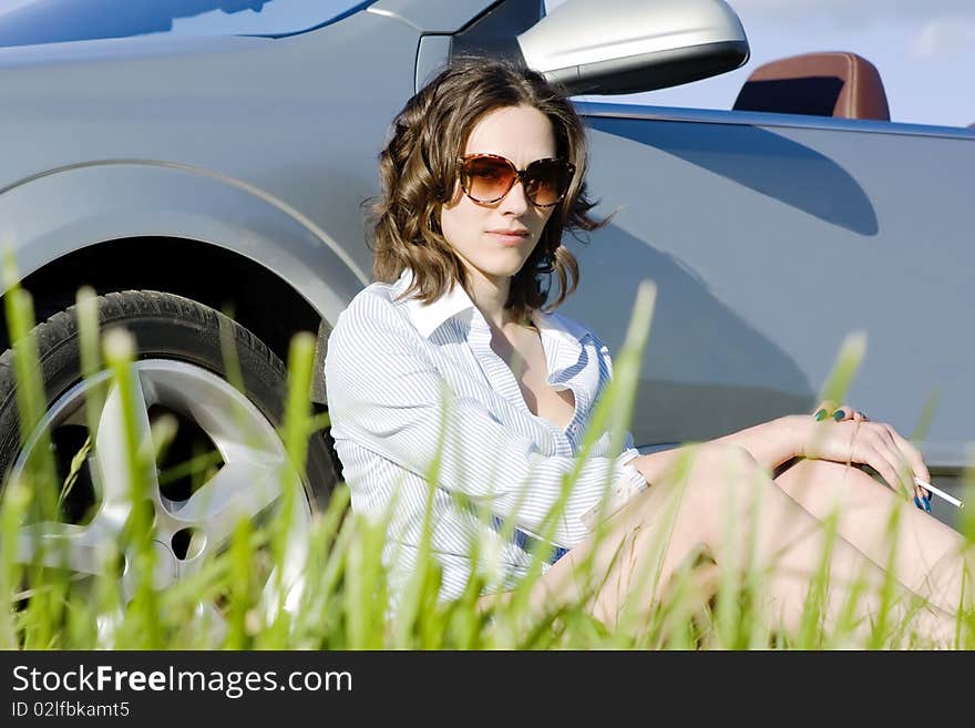 Young woman is sitting near her car and having a rest after a long trip. Young woman is sitting near her car and having a rest after a long trip