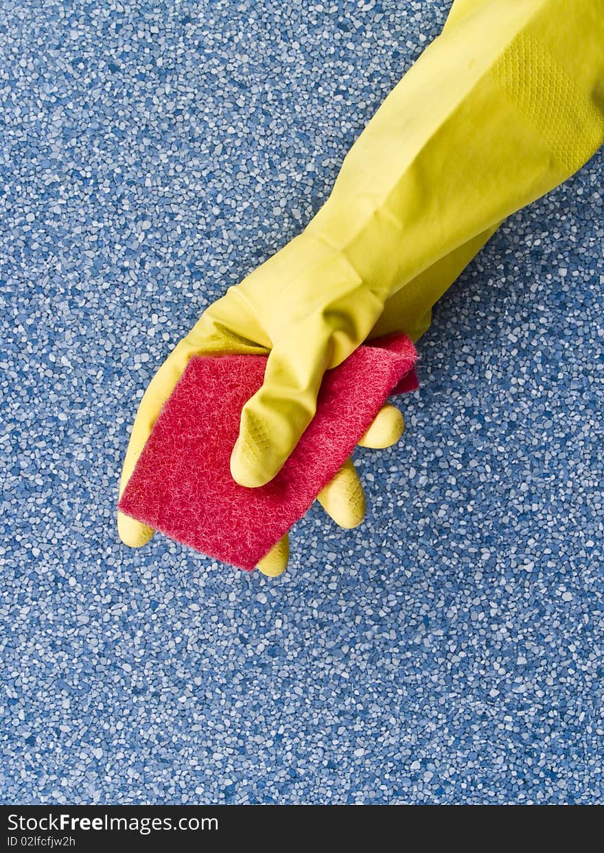 Hand in yellow glove holding,  grab the red sponge on the table. Hand in yellow glove holding,  grab the red sponge on the table