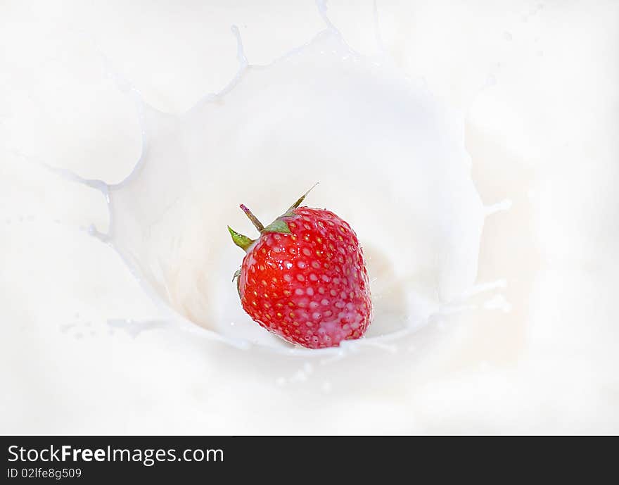 Fresh red strawberry splashing into milk or yogurt