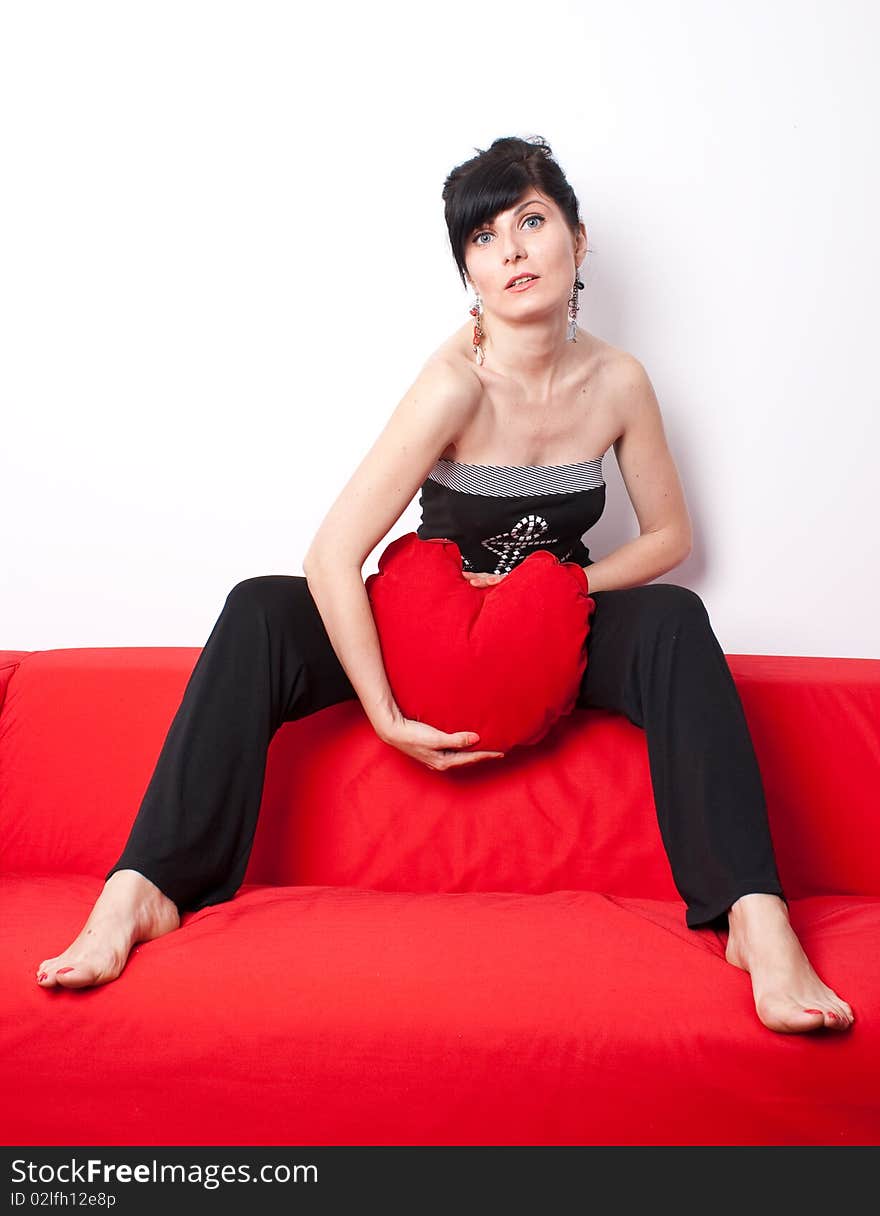 Woman playing with a heart shaped pillow. Woman playing with a heart shaped pillow