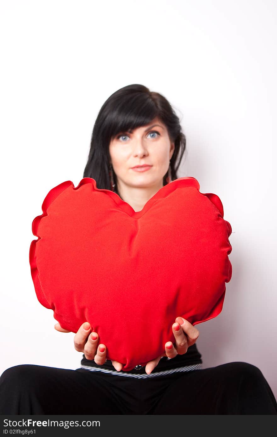 Woman offering a heart shpaed pillow (focus on heart). Woman offering a heart shpaed pillow (focus on heart)