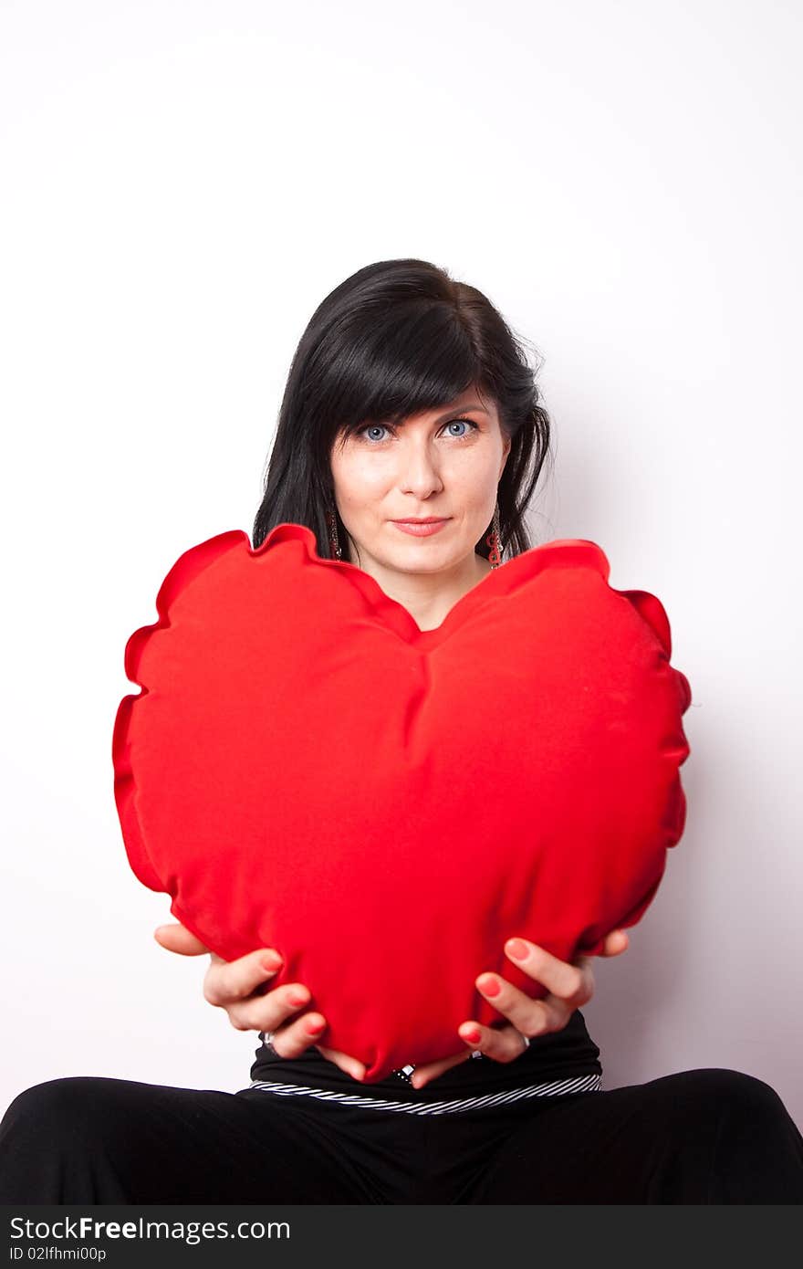 Woman offering a heart shpaed pillow (focus on face). Woman offering a heart shpaed pillow (focus on face)