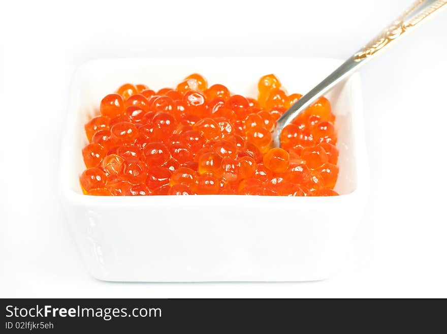 Teaspoon in red caviar over white background