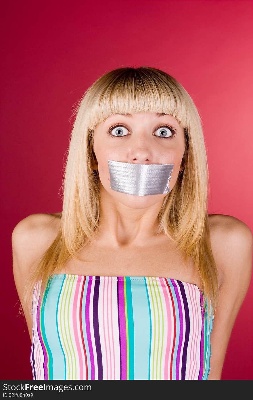 The frightened blonde on a red background in a striped shirt. The frightened blonde on a red background in a striped shirt