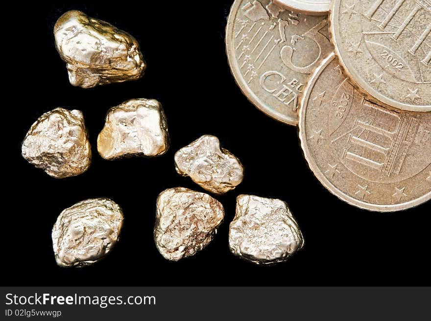 Gold nuggets and money, euro coins on a black background. closeup.