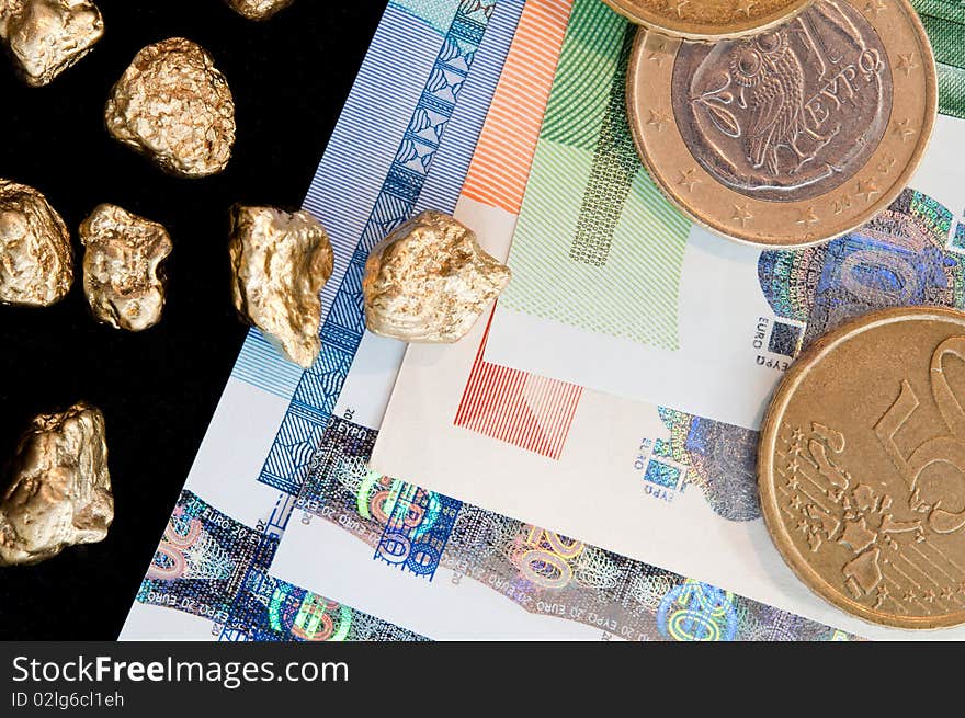 Gold nuggets and money, euro coins on a black background. closeup.