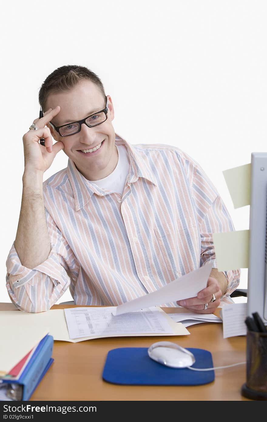 A man is seated at a computer desk and smiling at the camera.  Vertical shot.  Isolated on white. A man is seated at a computer desk and smiling at the camera.  Vertical shot.  Isolated on white.