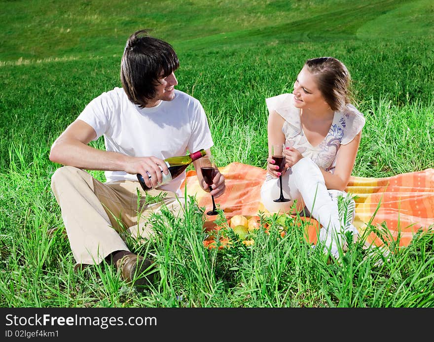 Smiling girl and boy with wine on grass