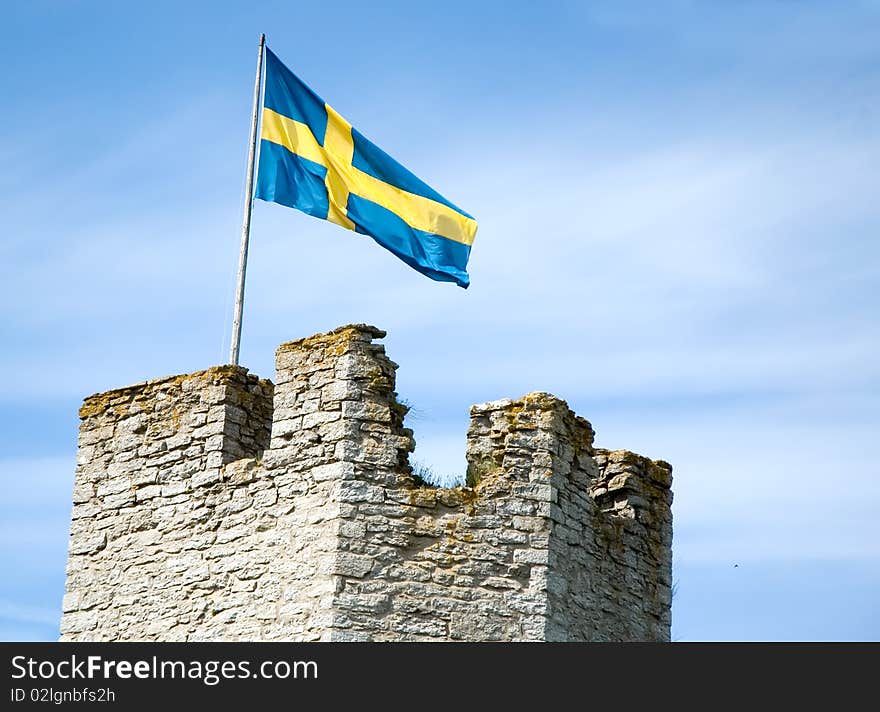 A Swedish flag flying over a medieval wall on Gotland