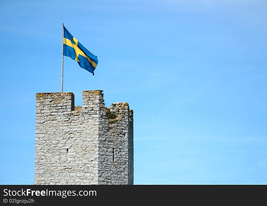 A Swedish flag flying over a medieval wall on Gotland