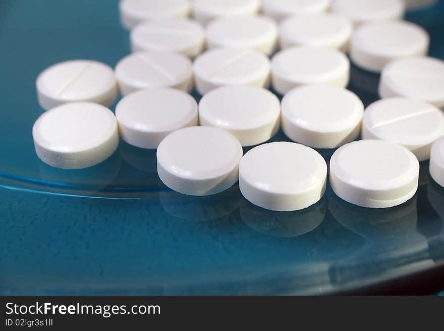 White pressed medicinal pill on blue background. White pressed medicinal pill on blue background