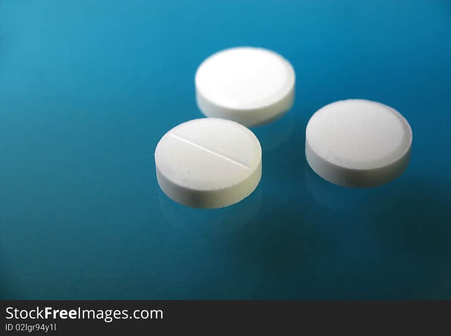 White pressed medicinal pill on blue background. White pressed medicinal pill on blue background